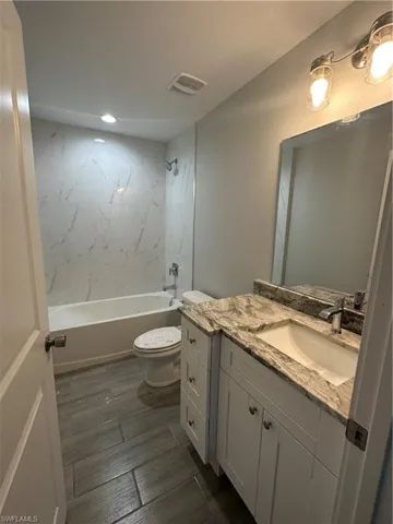 Full bathroom featuring toilet, tiled shower / bath combo, and vanity