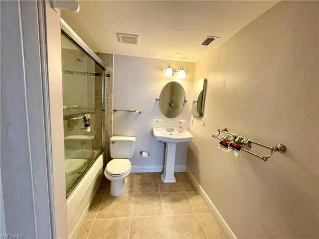 Full guest bathroom featuring sink, tile patterned flooring, giving guests a master suiteshower / bath combination with glass door, and toilet