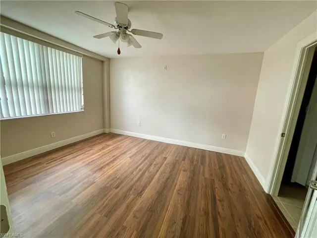 Unfurnished guest bedroom featuring dark wood-type flooring and ceiling fan