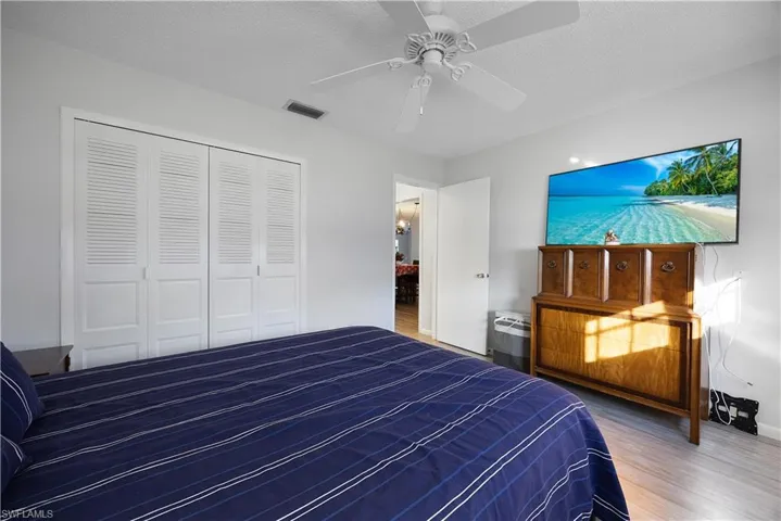 Bedroom featuring a textured ceiling, wood finished floors, a closet, and a ceiling fan