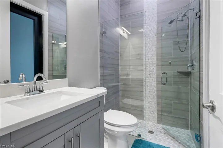 Bathroom featuring a shower with door, toilet, tile patterned floors, and vanity