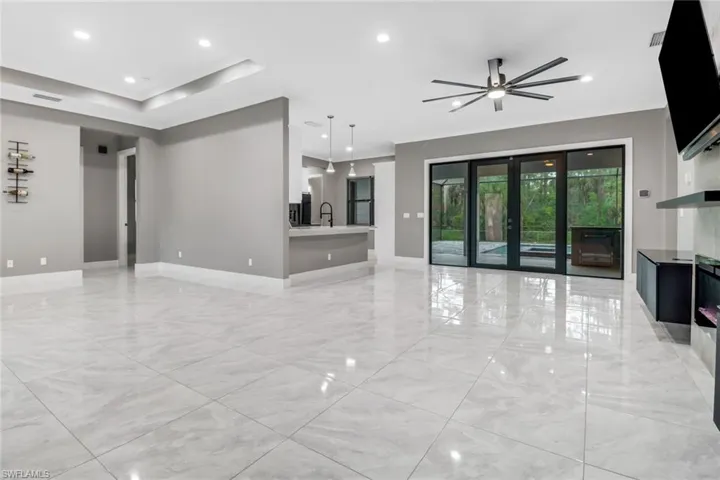 Unfurnished living room featuring ceiling fan, light tile patterned floors, and french doors