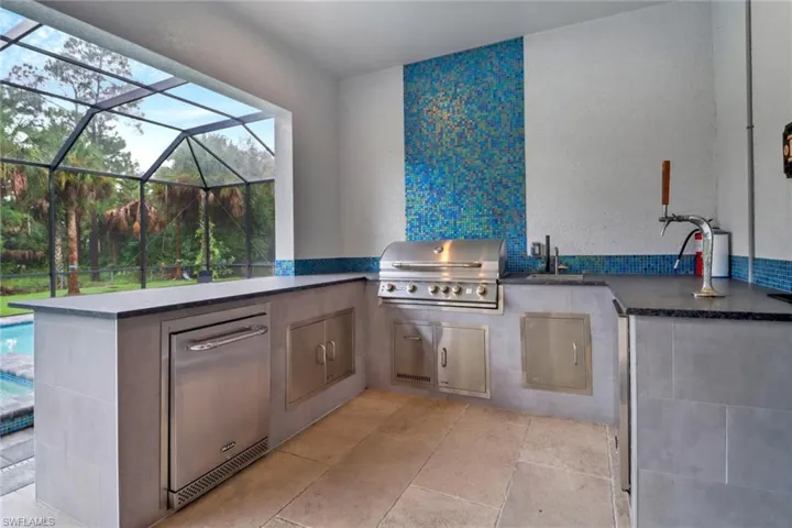 View of patio with area for grilling, sink, and glass enclosure