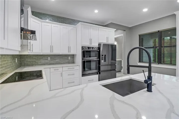 Kitchen featuring sink, tasteful backsplash, appliances with stainless steel finishes, and light stone counters