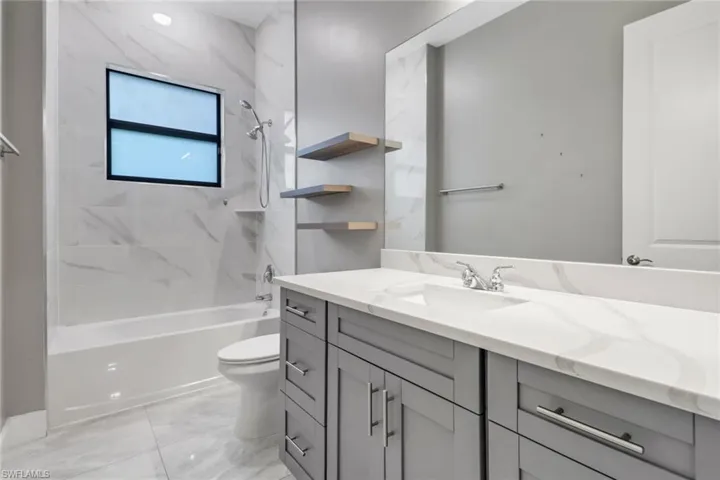Full bathroom with toilet, tiled shower / bath combo, vanity, and tile patterned floors