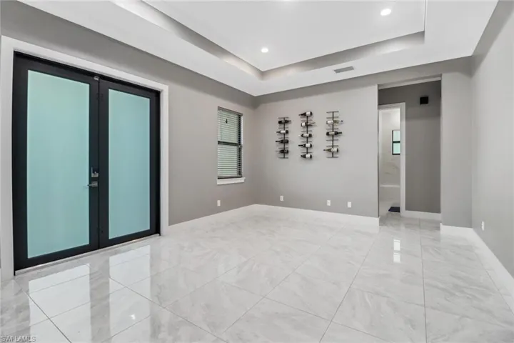 Spare room featuring a tray ceiling, light tile patterned flooring, and french doors