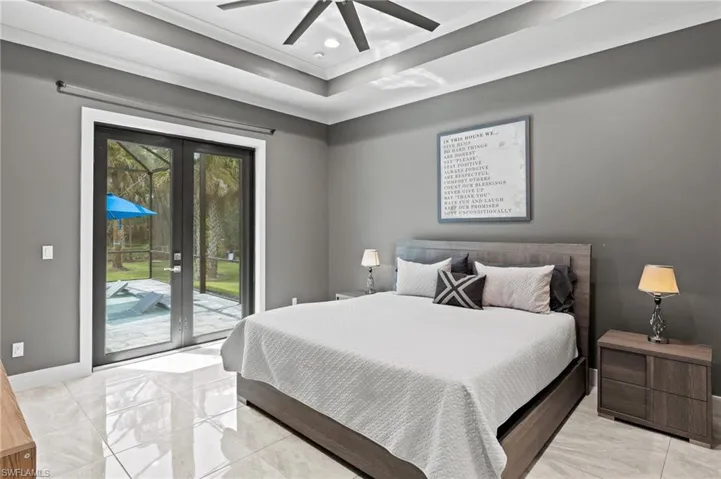 Bedroom featuring ceiling fan, access to exterior, a tray ceiling, and light tile patterned floors