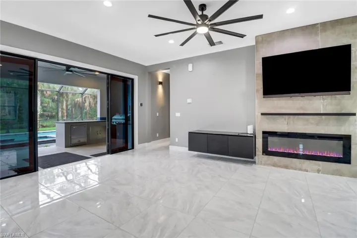 Unfurnished living room featuring a fireplace, tile walls, ceiling fan, and light tile patterned flooring
