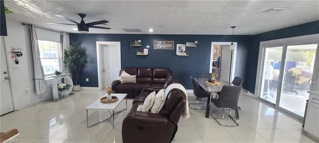 Living area featuring light tile patterned flooring, a ceiling fan, and recessed lighting