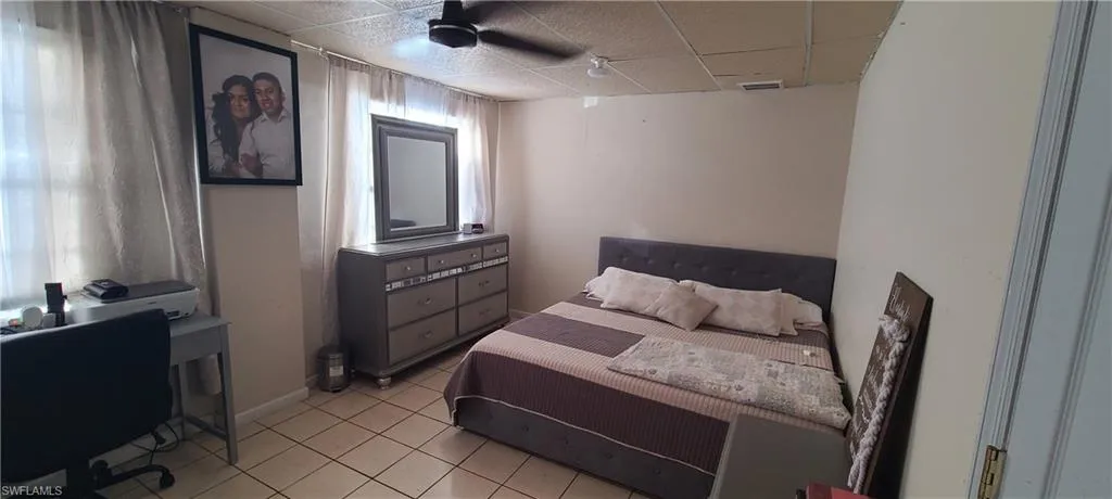 Bedroom with a drop ceiling and light tile patterned floors