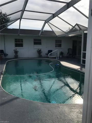 Swimming pool with glass enclosure, a sunroom, and a patio area