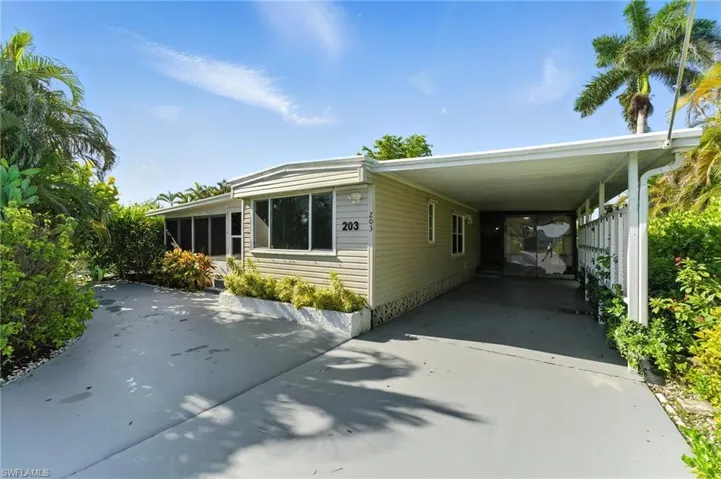 View of property exterior with concrete driveway and a carport