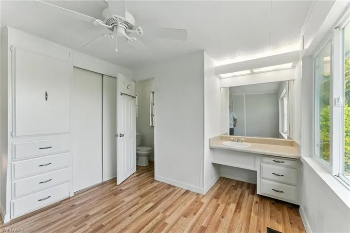 Bathroom with vanity, wood finished floors, healthy amount of natural light, and ceiling fan