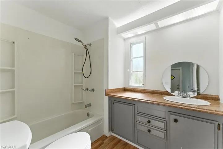 Bathroom featuring vanity, shower / bath combination, and wood finished floors