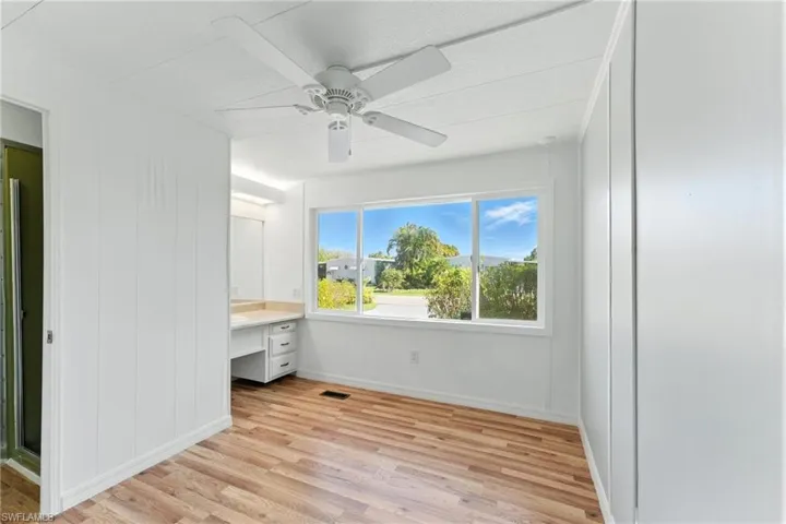 Unfurnished bedroom featuring light wood finished floors, a desk, and a ceiling fan
