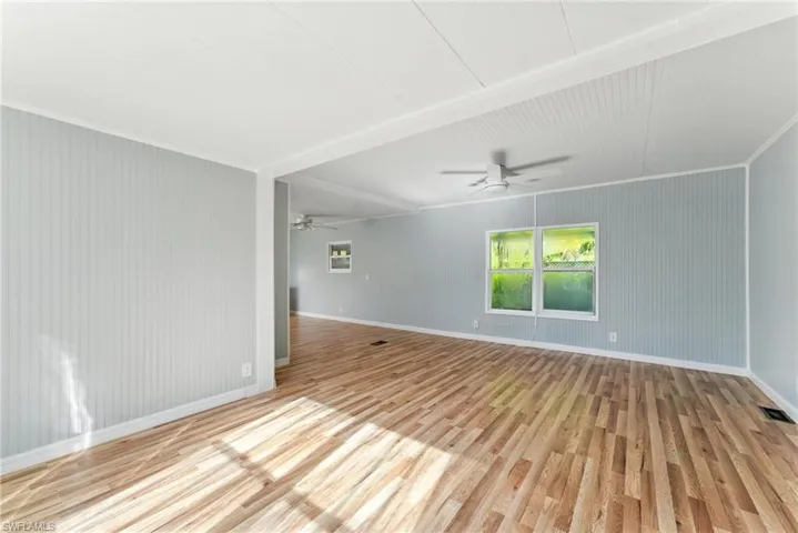 Spare room with wood finished floors, a ceiling fan, and ornamental molding