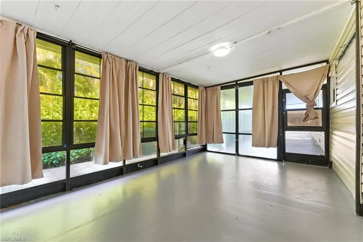 Unfurnished sunroom featuring concrete floors and a wall of windows