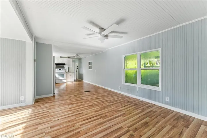 Unfurnished living room featuring light wood finished floors, ceiling fan, and ornamental molding