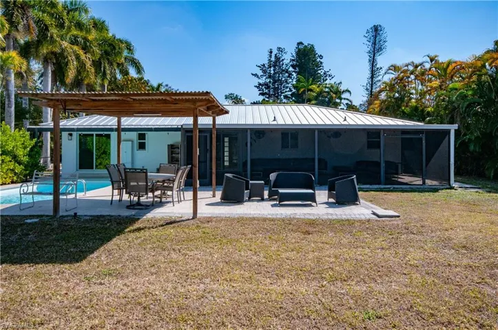 Rear view of house with a pergola, a yard, a patio area, an outdoor pool, and a metal roof