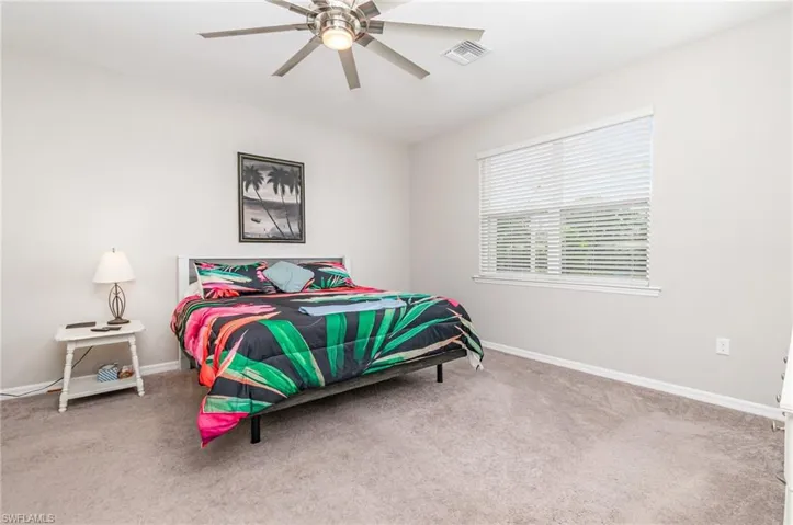 Bedroom with light carpet and a ceiling fan