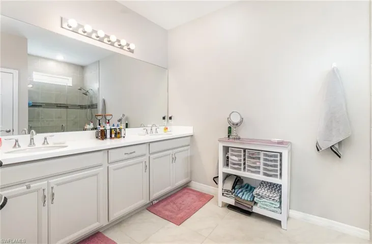 Full bath featuring double vanity, light tile patterned floors, and a stall shower