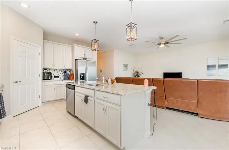 Kitchen with hanging light fixtures, stainless steel appliances, open floor plan, white cabinetry, and light tile patterned floors