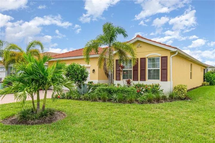 View of front of home with stucco siding, a front lawn, an attached garage, and a tile roof