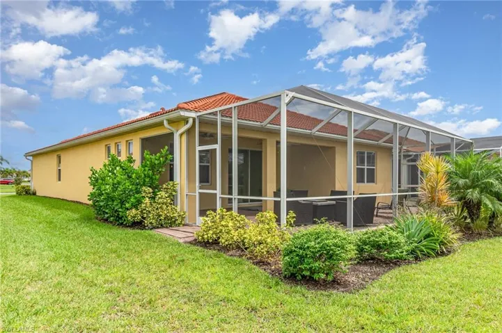 Back of property featuring a lawn, a lanai, a sunroom, and stucco siding