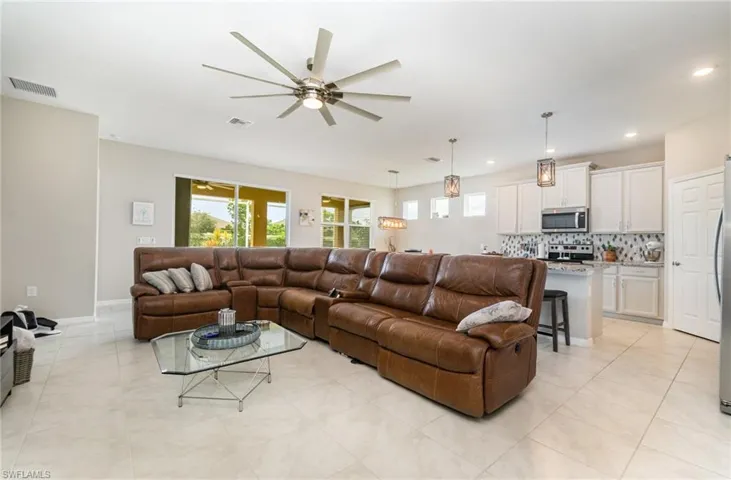 Living room with ceiling fan, light tile patterned floors, and recessed lighting