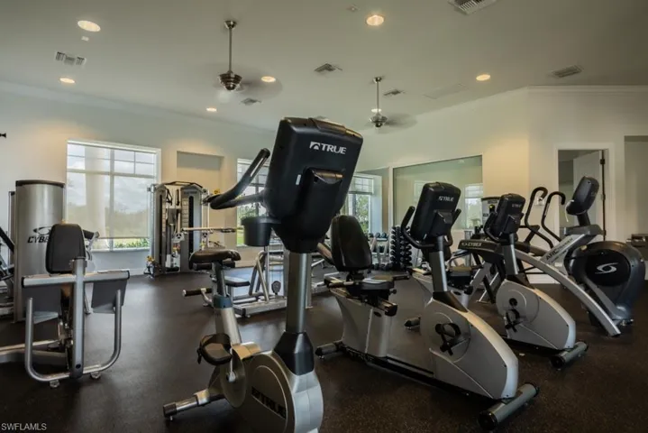 Gym with ornamental molding, plenty of natural light, and recessed lighting