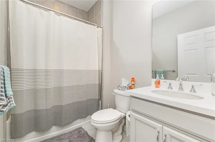 Full bath featuring vanity, shower / bath combo with shower curtain, and tile patterned floors
