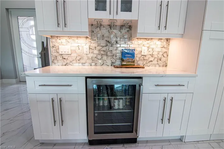 Bar featuring white cabinets and beverage cooler