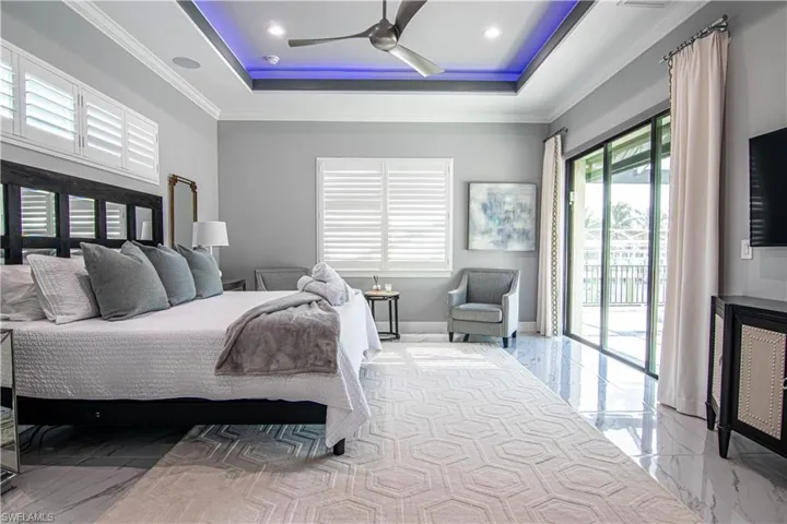 Bedroom with ceiling fan, access to exterior, ornamental molding, and a tray ceiling