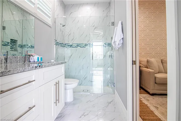 Bathroom featuring tile walls, an enclosed shower, vanity, and toilet