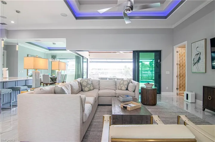 Living room featuring ceiling fan, ornamental molding, a healthy amount of sunlight, and a tray ceiling