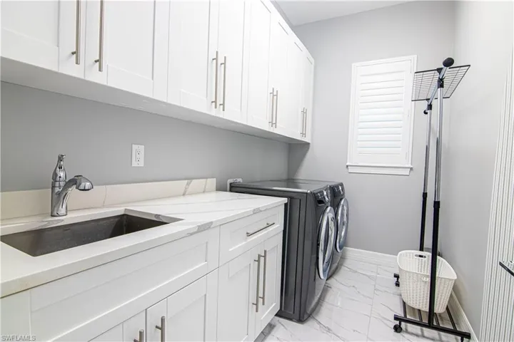 Washroom with cabinets, sink, and washing machine and clothes dryer