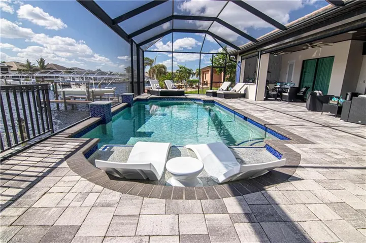 View of swimming pool featuring a lanai, ceiling fan, a patio area, and a water view