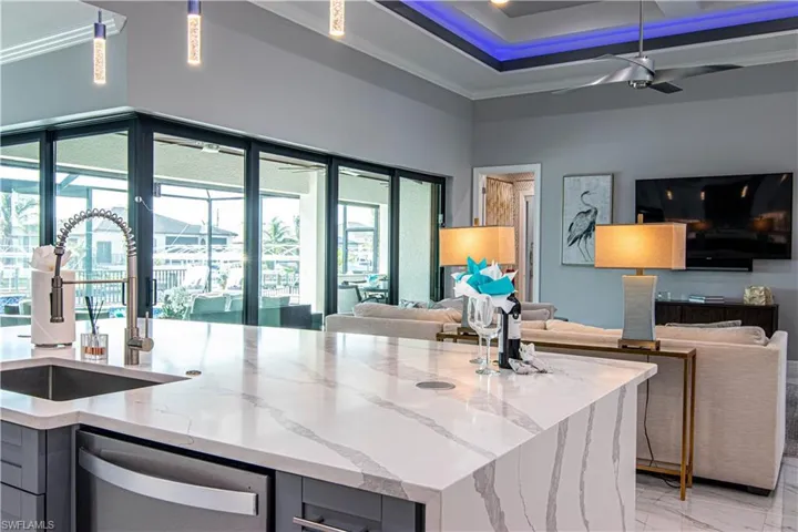 Kitchen featuring ceiling fan, a center island, light stone countertops, stainless steel dishwasher, and sink