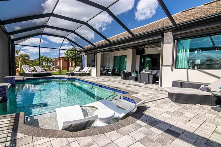View of swimming pool featuring an outdoor living space, glass enclosure, and a patio area