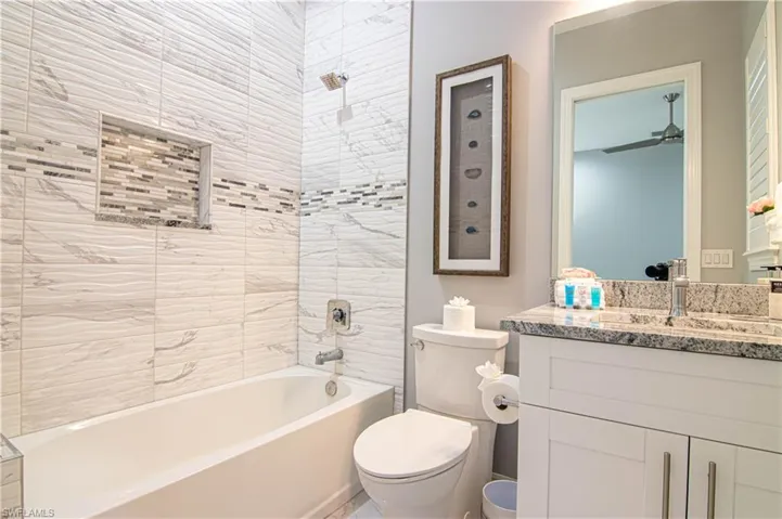 Full bathroom featuring toilet, tiled shower / bath combo, ceiling fan, and vanity