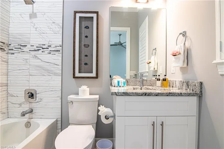 Full bathroom with toilet, tiled shower / bath, and vanity
