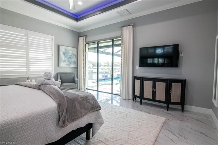 Bedroom with ceiling fan, access to exterior, crown molding, and a raised ceiling