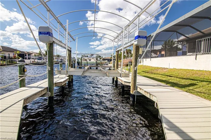 Dock area featuring a water view, a yard, and glass enclosure