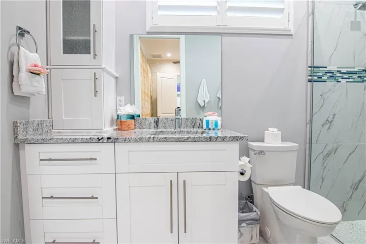 Bathroom featuring a shower with door, toilet, and vanity