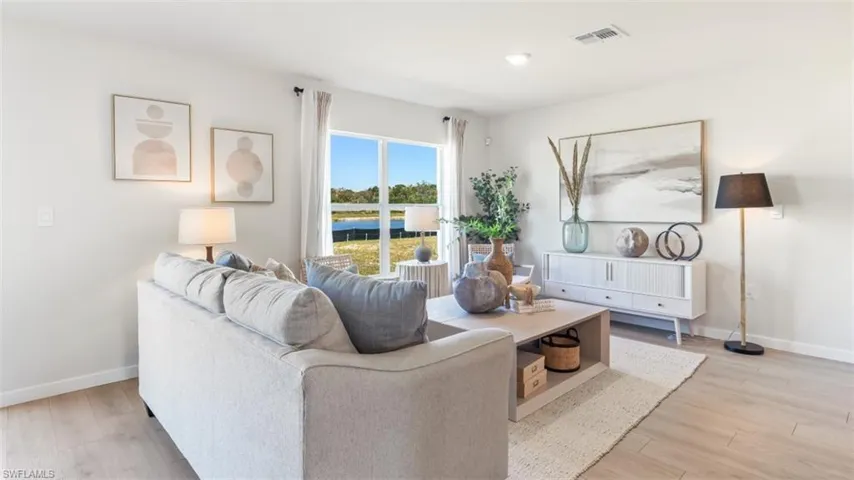 MODEL PHOTO - Living area with a water view and light wood-style flooring