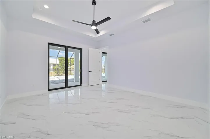 Spare room with a raised ceiling, baseboards, a ceiling fan, and visible vents