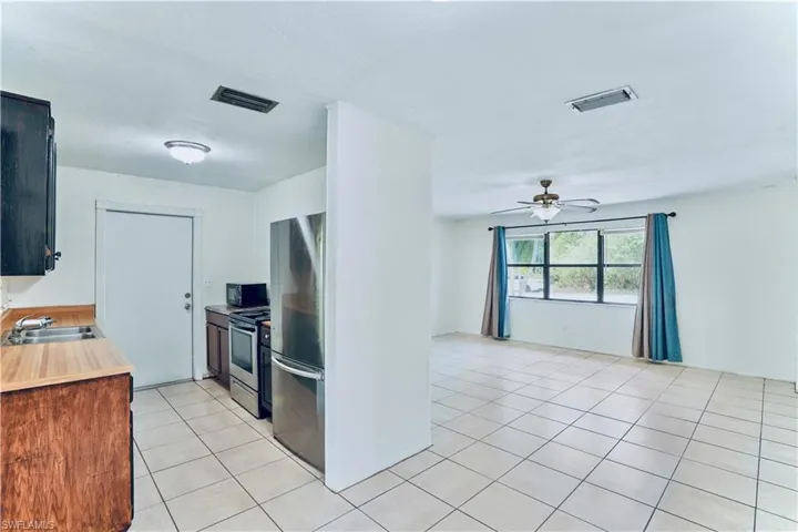 Kitchen with a sink, appliances with stainless steel finishes, light tile patterned floors, ceiling fan, and open floor plan