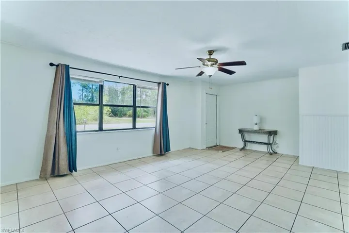 Empty room with ceiling fan and light tile patterned floors