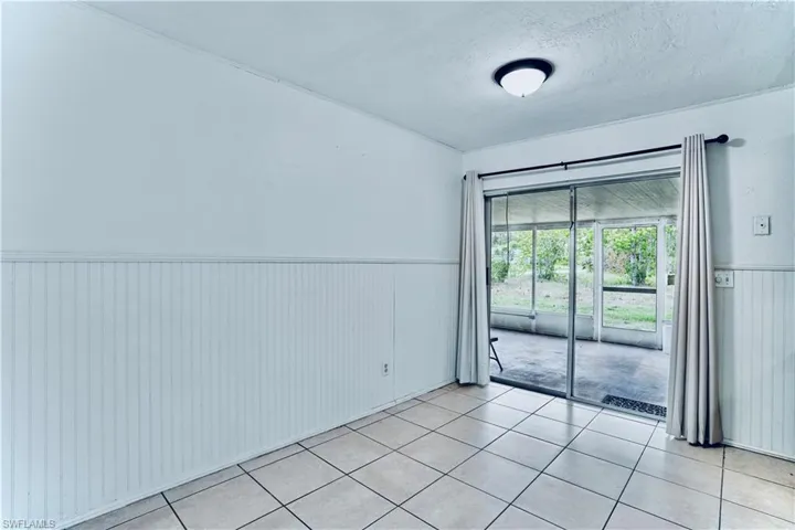 Unfurnished room featuring a wainscoted wall, light tile patterned flooring, and a textured ceiling