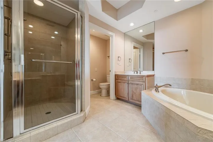Bathroom featuring vanity, a stall shower, light tile patterned floors, recessed lighting, and a bath